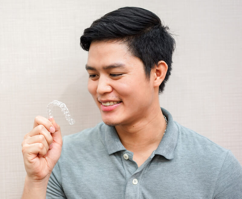 teenage boy holding clear aligners